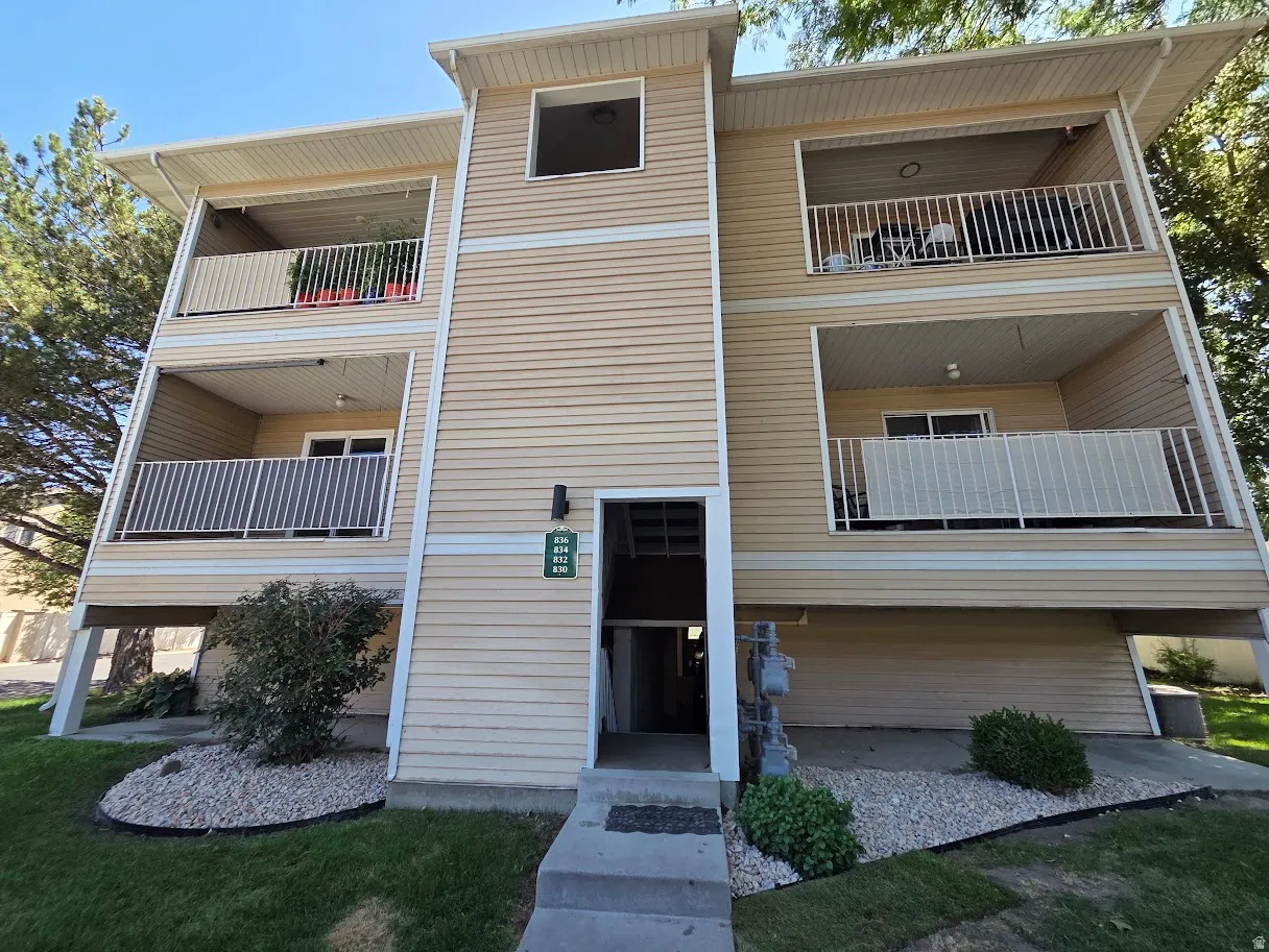 Multi-level exterior featuring light-toned horizontal siding, white railings, and covered balconies.
