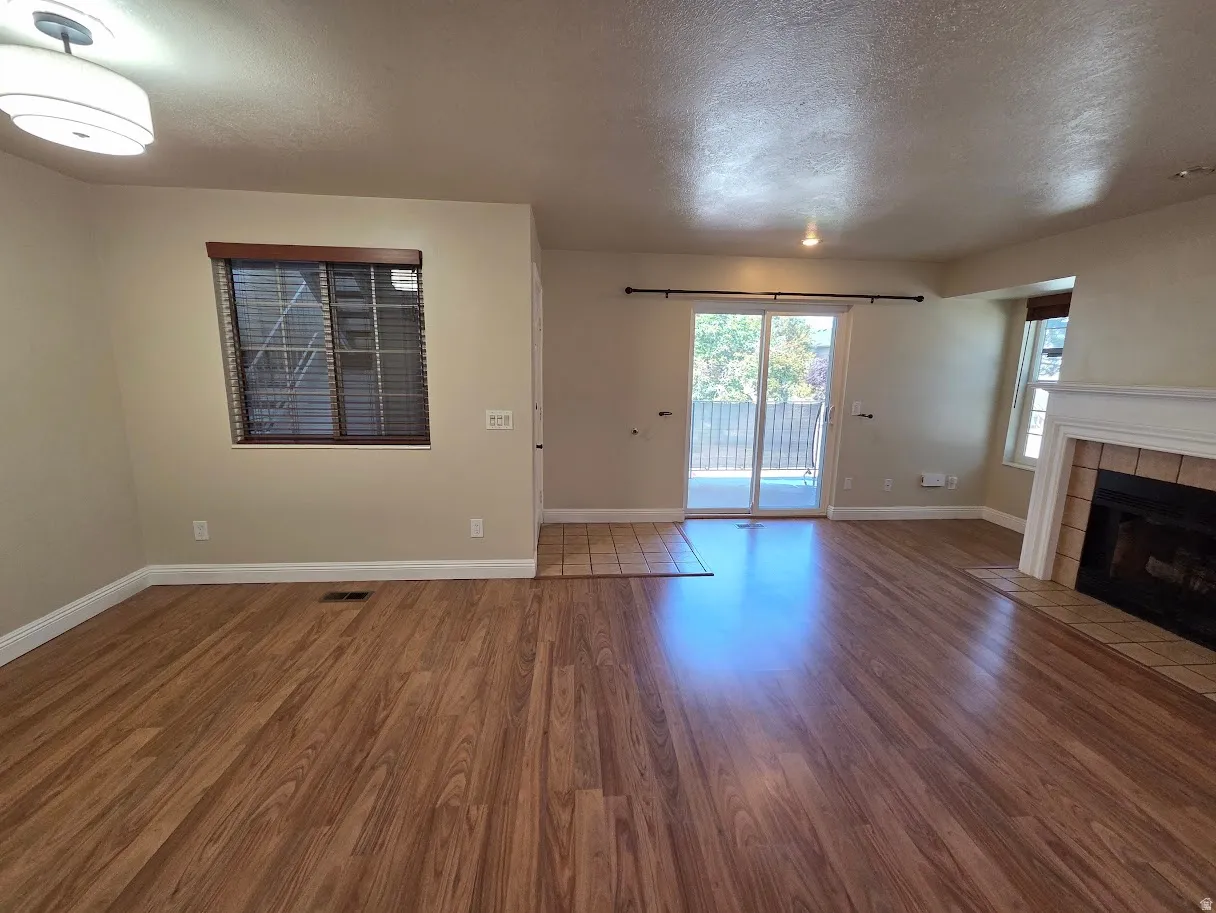 Wood-finish flooring throughout, complemented by a tiled hearth surrounding a fireplace with a mantel