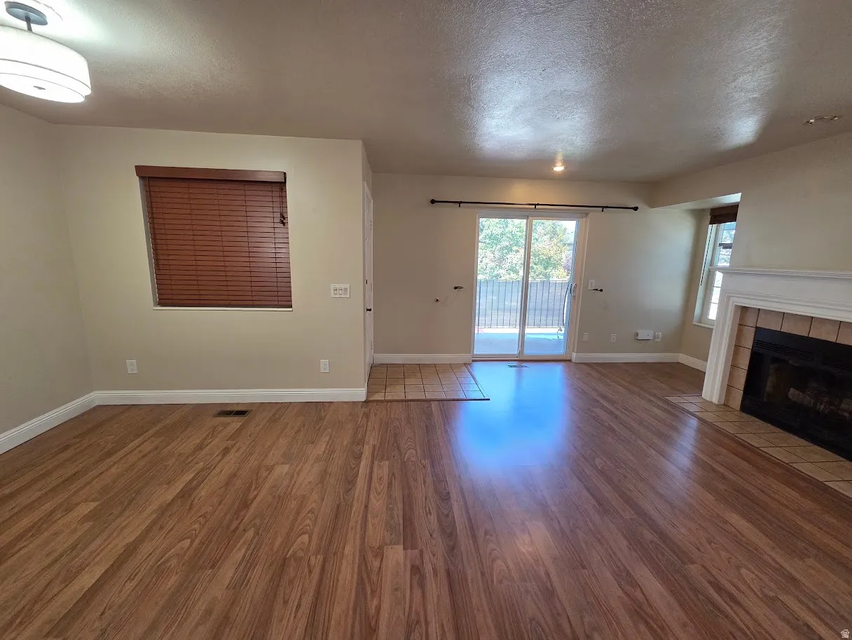 Living area featuring wood-finish flooring, a fireplace with a tile surround and white mantel, and a sliding glass door