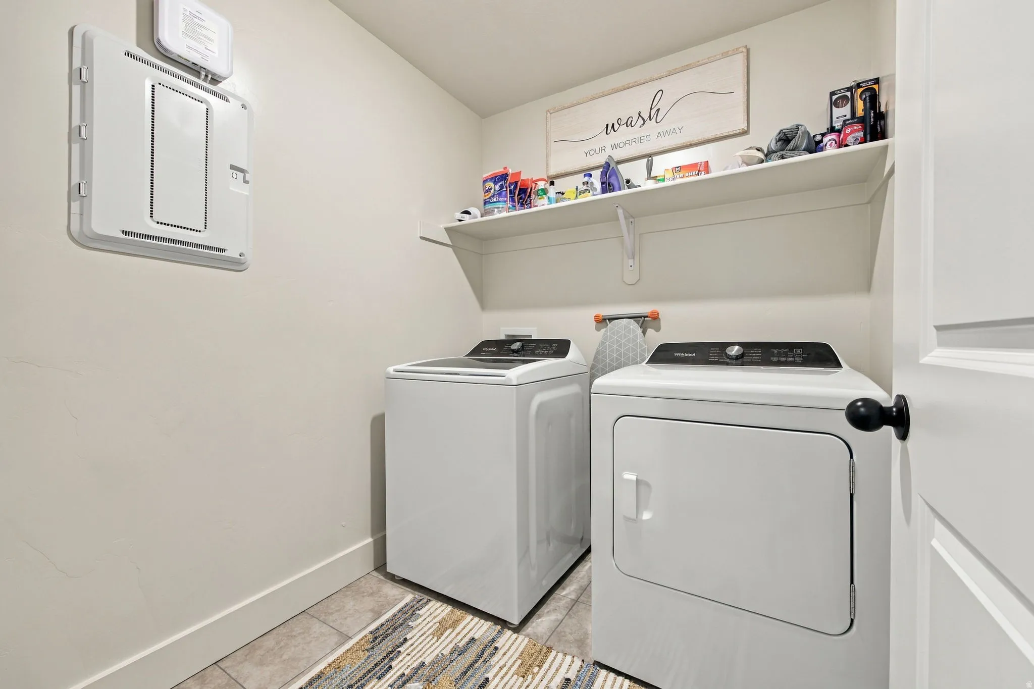Laundry area featuring a wall-mounted shelf, light-toned walls, and tile flooring