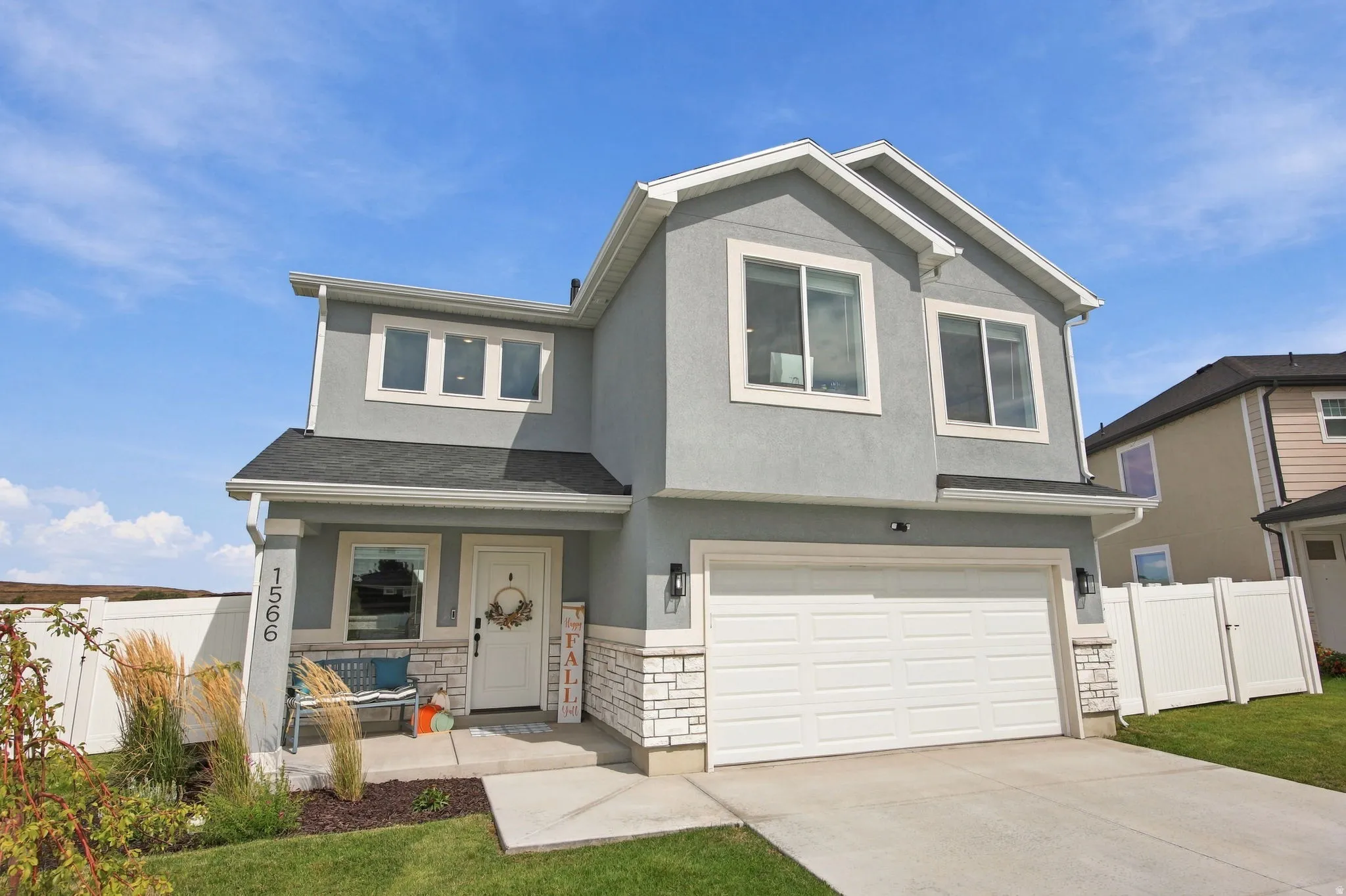 Stucco exterior with stone accenting, prominent garage, covered entryway, and second-story windows