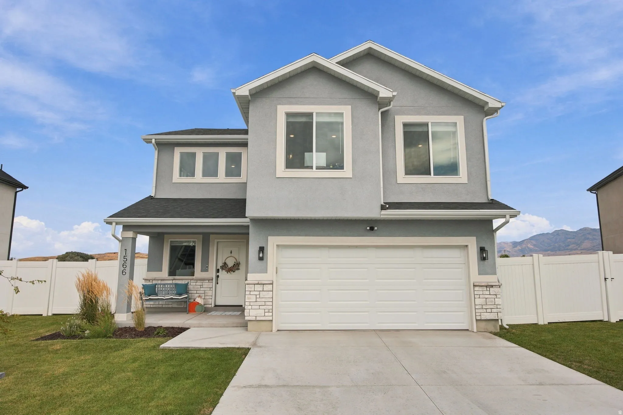 Contemporary exterior featuring a two-story design, attached garage, stone accents, covered front porch, and a concrete driveway