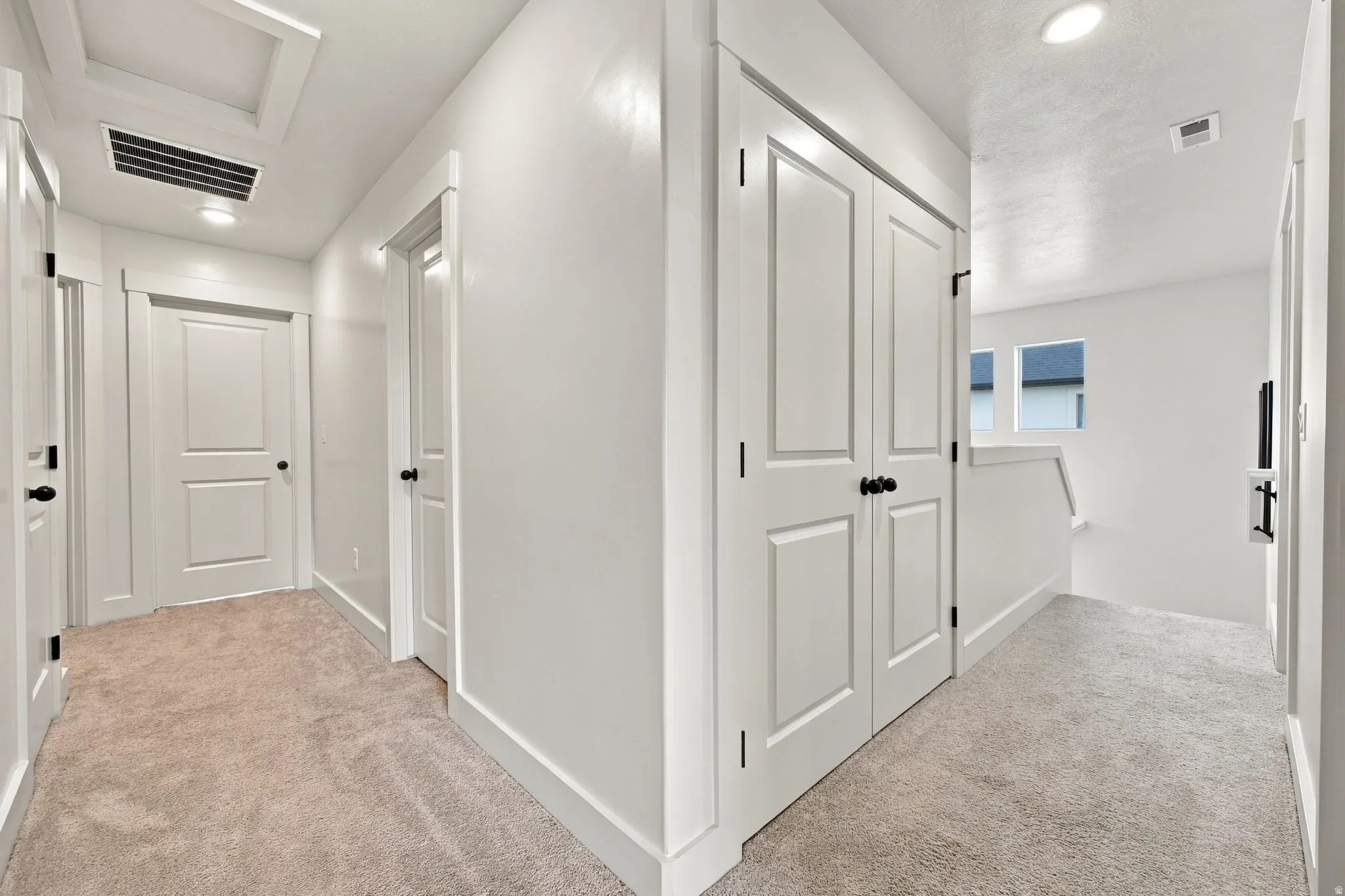 Recessed ceiling lighting, white interior doors, and neutral carpeting