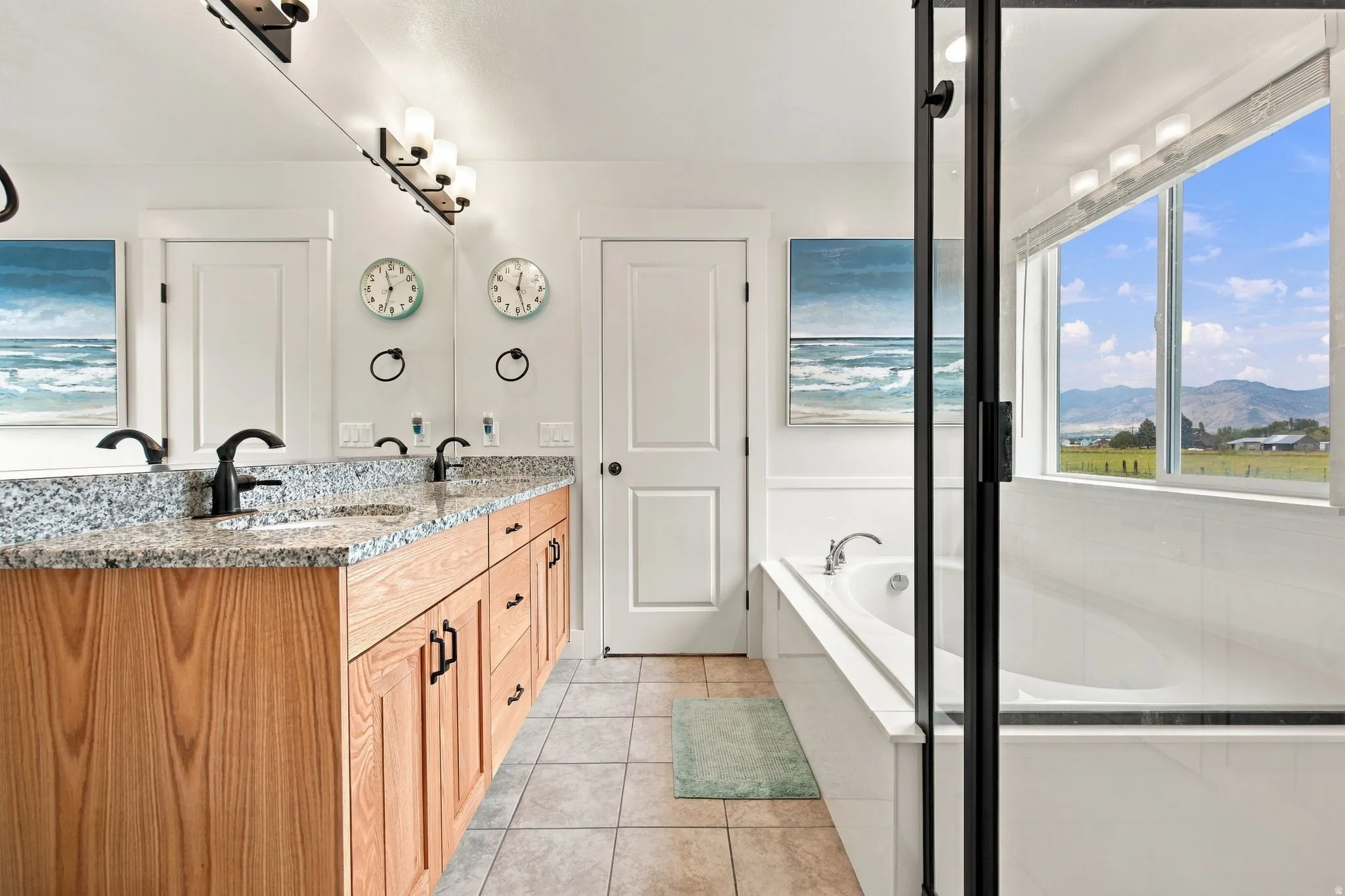 Double vanity with granite countertop, wood-finish cabinetry, and matte black fixtures