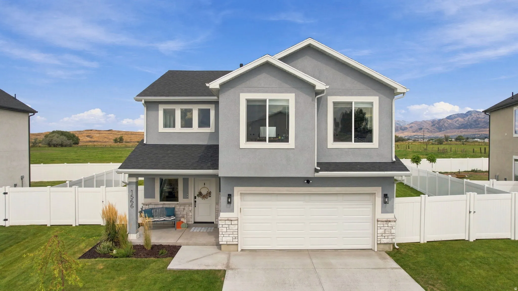 Two-story stucco exterior with stone accents, attached two-car garage, and a covered porch
