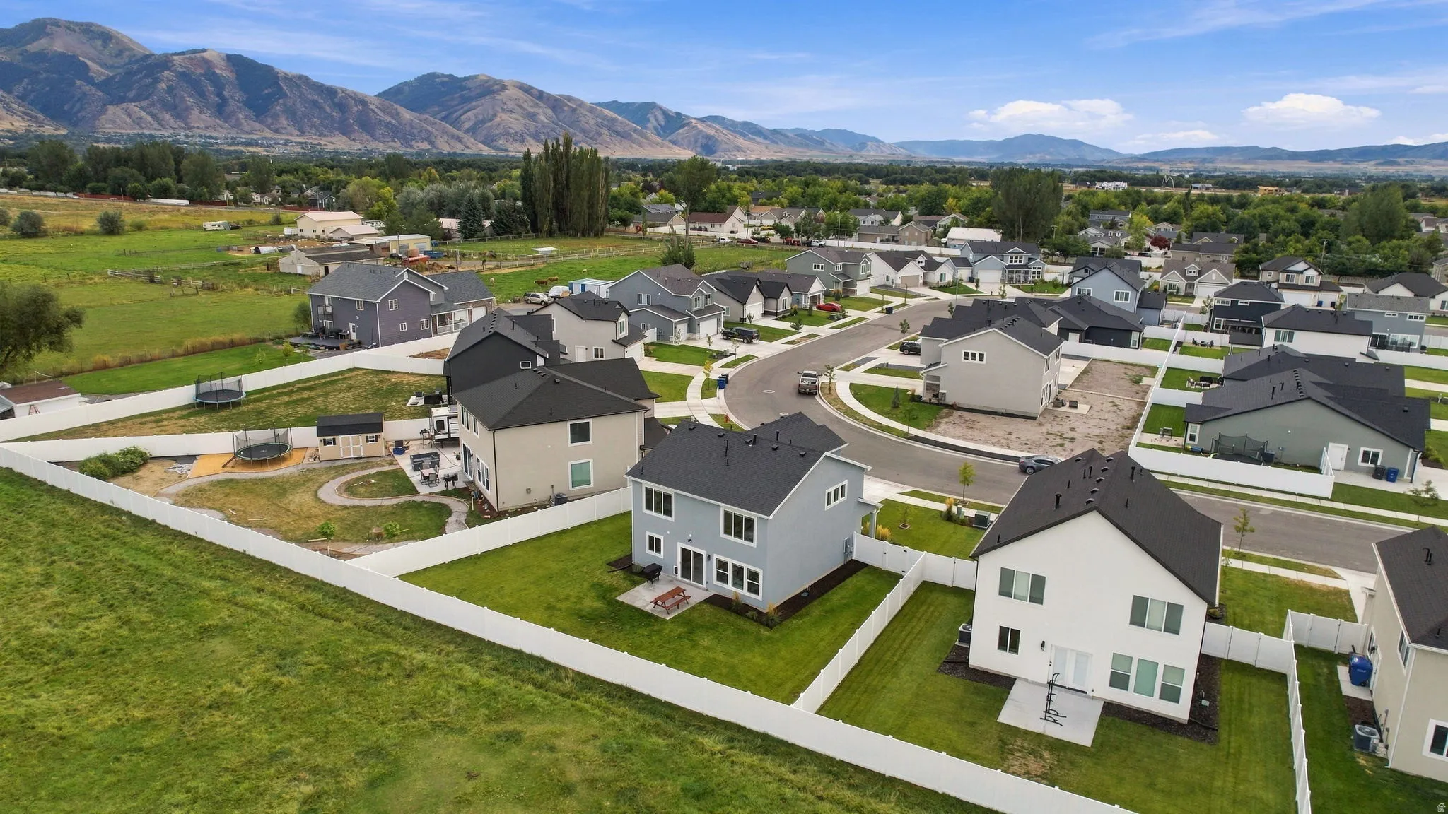 Residential neighborhood with a mountain backdrop, featuring a cul-de-sac and white perimeter fencing