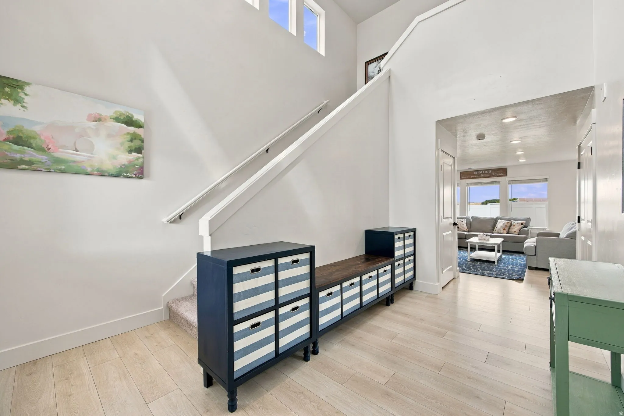 Two-story entry with wood-finish flooring, white walls, and a staircase featuring a white railing