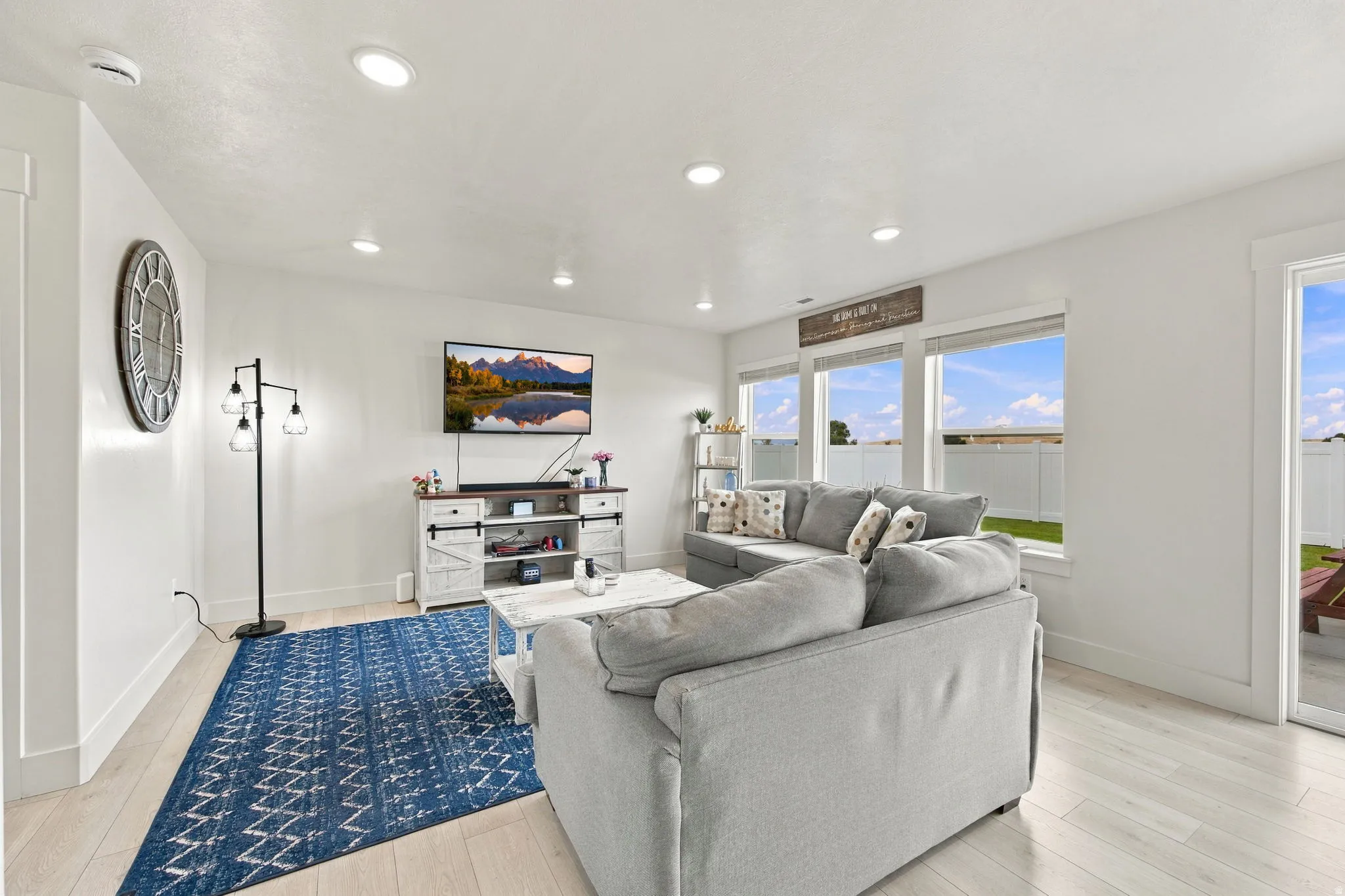 Recessed ceiling lighting, wood-finish flooring, multiple windows, and a sliding glass door