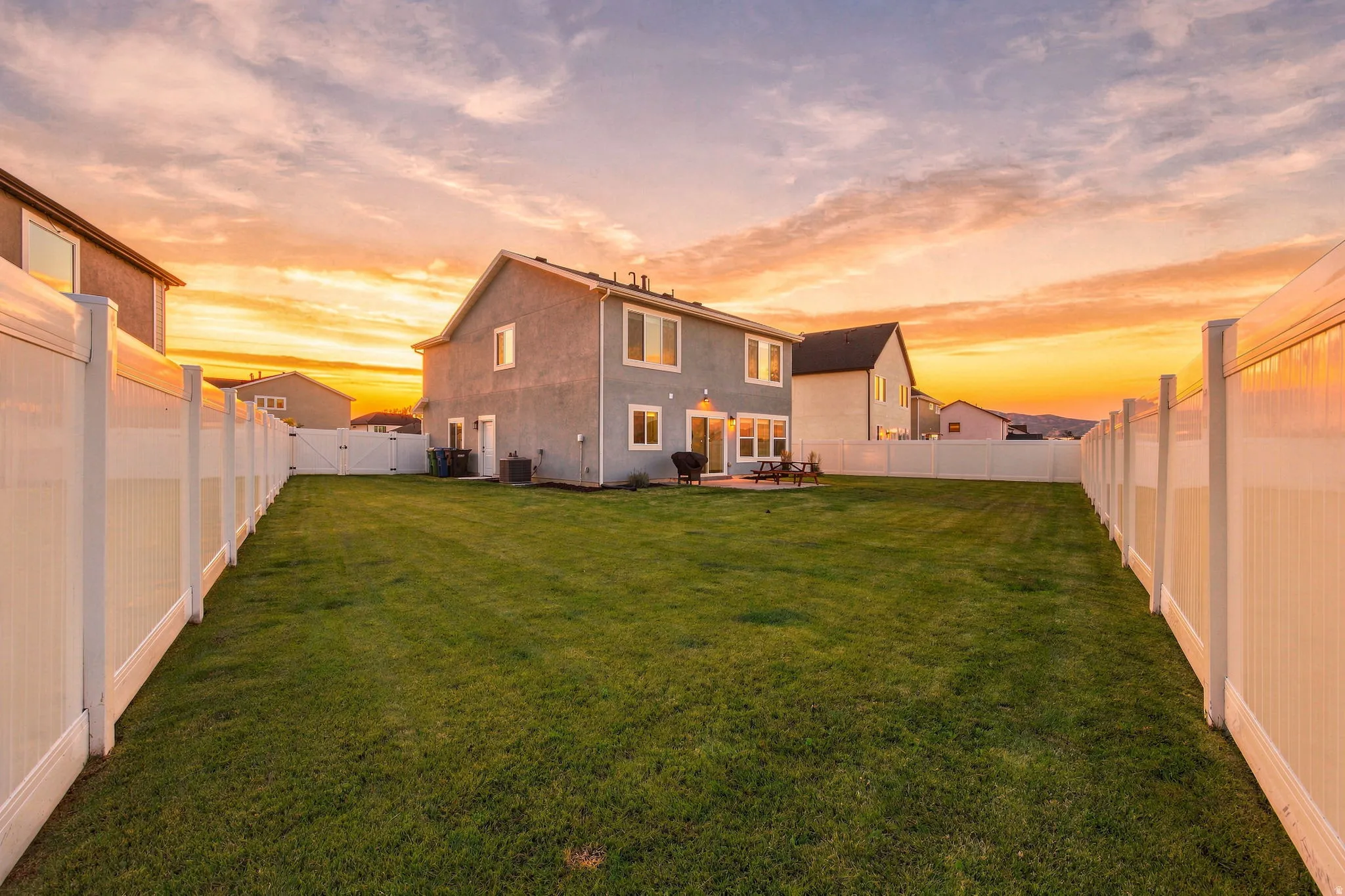 Expansive backyard featuring a manicured lawn, full perimeter fencing, and an exterior patio
