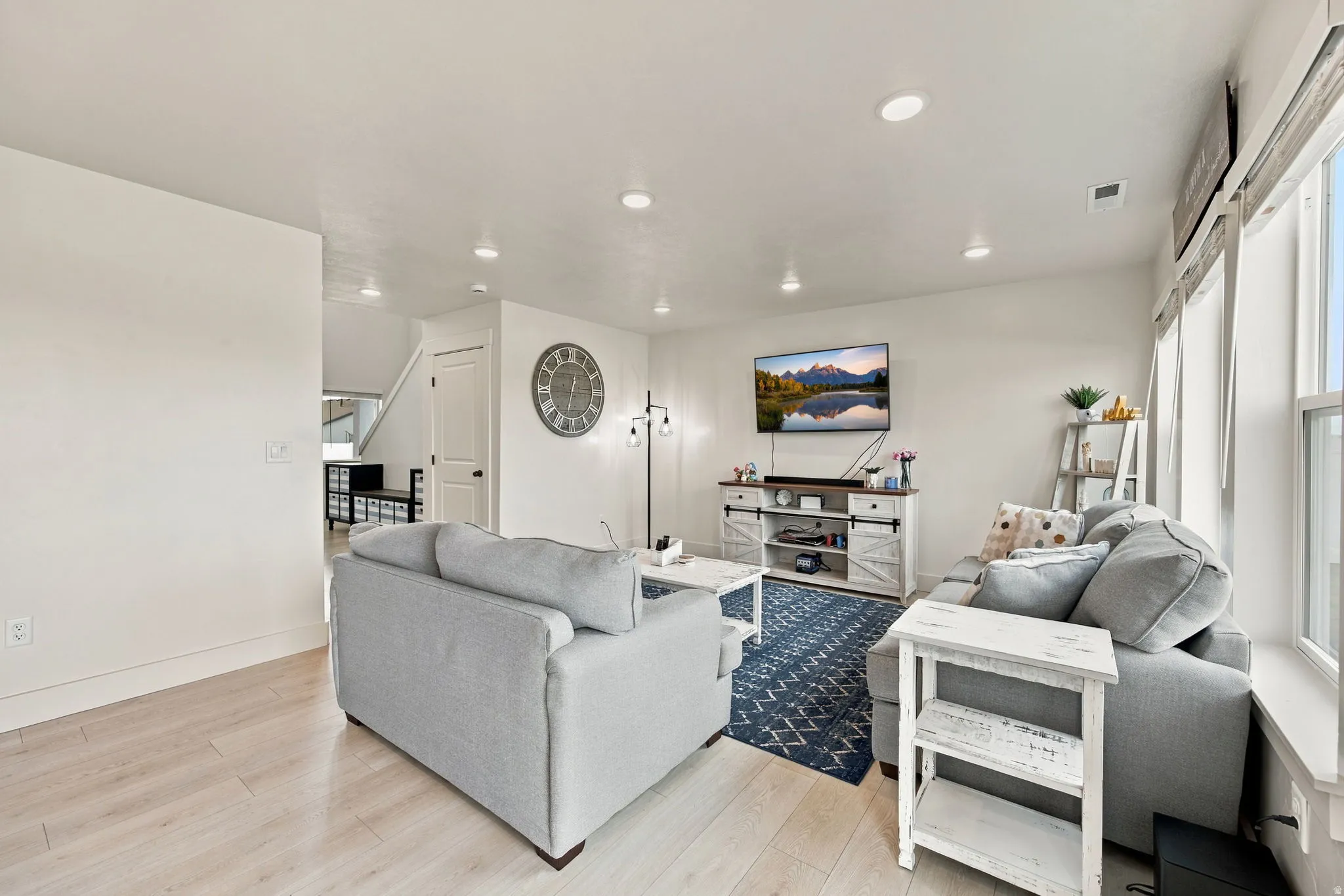 Recessed lighting, light wood-finish flooring, and multiple windows with blinds