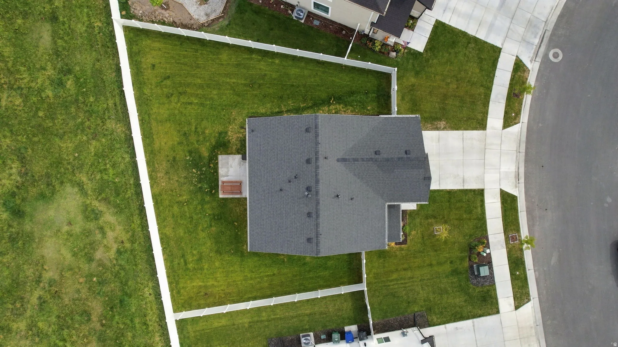 Expansive lot featuring a dark gray shingle roof, concrete driveway, and a concrete patio