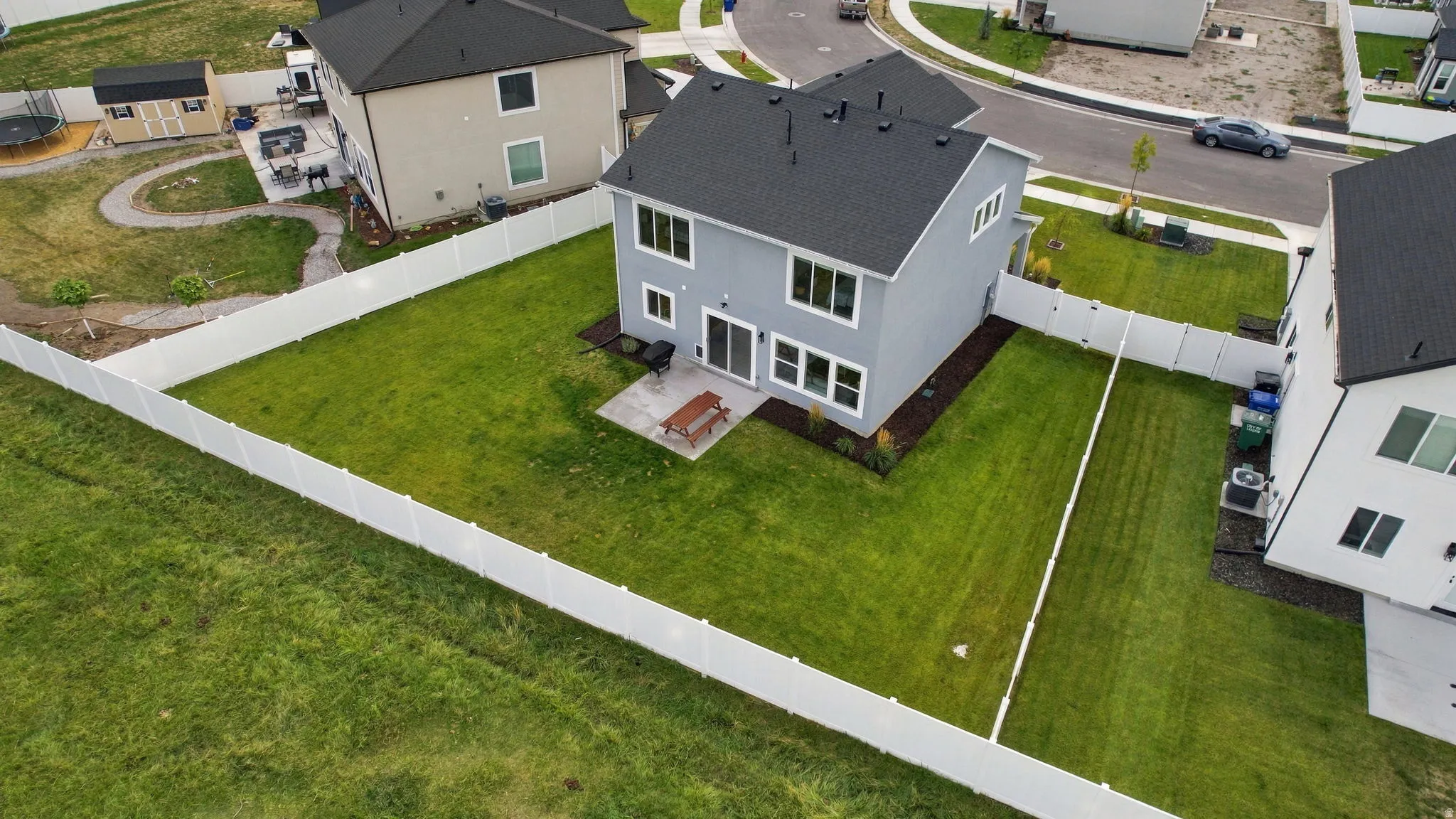 Expansive backyard featuring a manicured lawn, full privacy fencing, and a concrete patio
