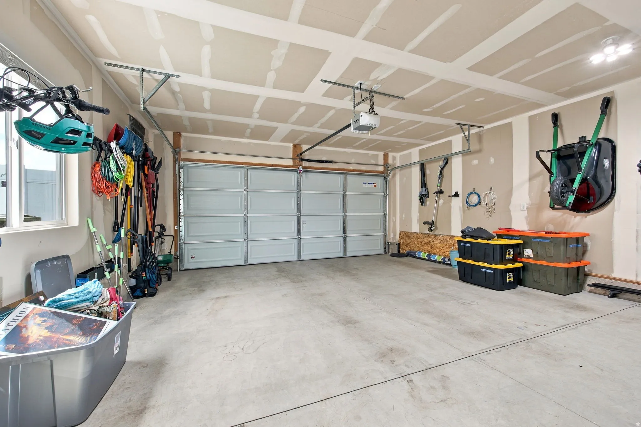 Attached two-car garage with concrete flooring, wall-mounted storage racks, and overhead garage door opener