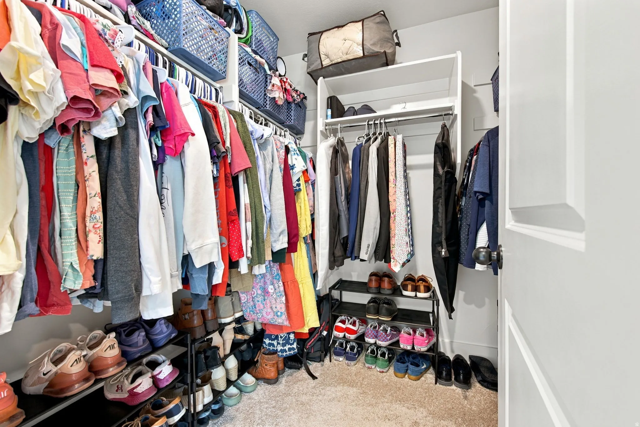 Built-in shelving, multiple hanging rods, and carpet flooring