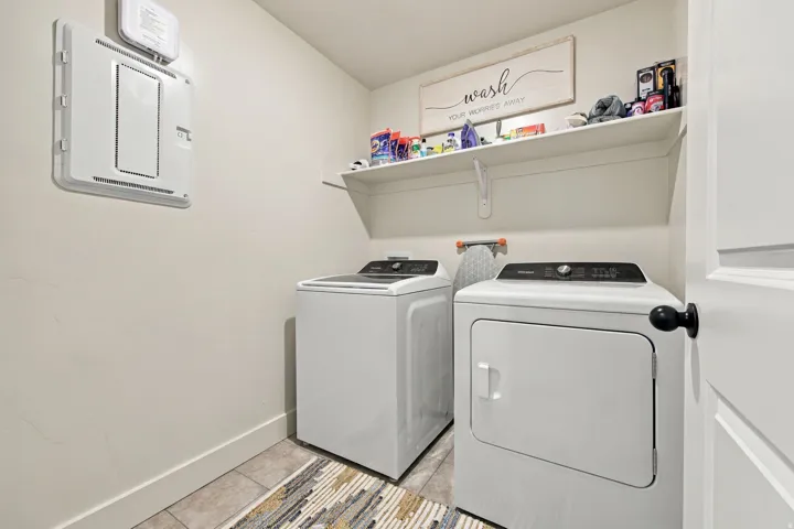 Laundry area featuring a wall-mounted shelf, light-toned walls, and tile flooring