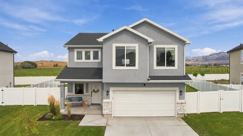 Two-story stucco exterior with stone accents, attached two-car garage, and a covered porch
