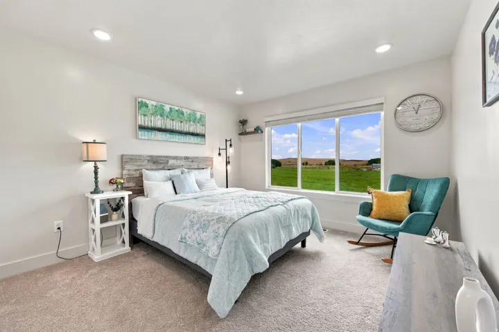 Recessed lighting, wood-finish headboard, window with exterior scenery, wall-to-wall carpeting, and bright white walls