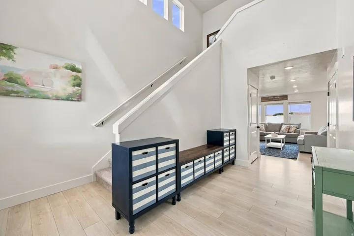 Two-story entry with wood-finish flooring, white walls, and a staircase featuring a white railing