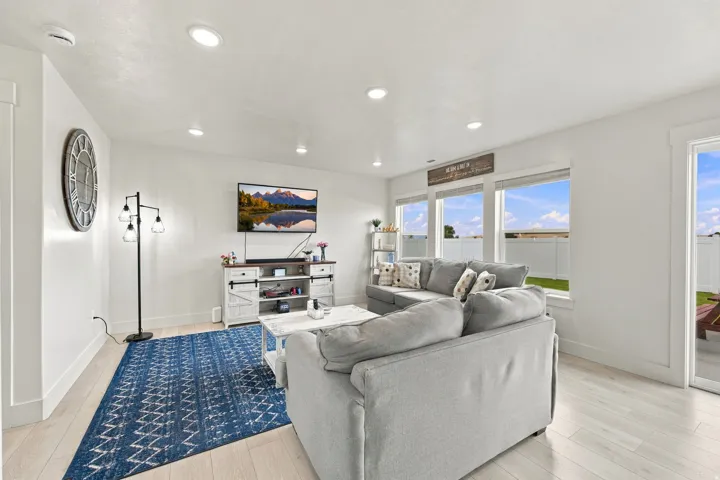 Recessed ceiling lighting, wood-finish flooring, multiple windows, and a sliding glass door