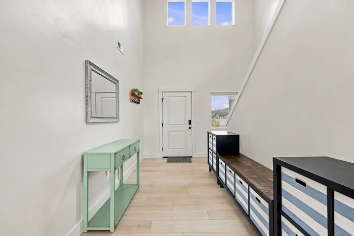 Vaulted entry with abundant natural light, light wood-finish flooring, and white interior walls