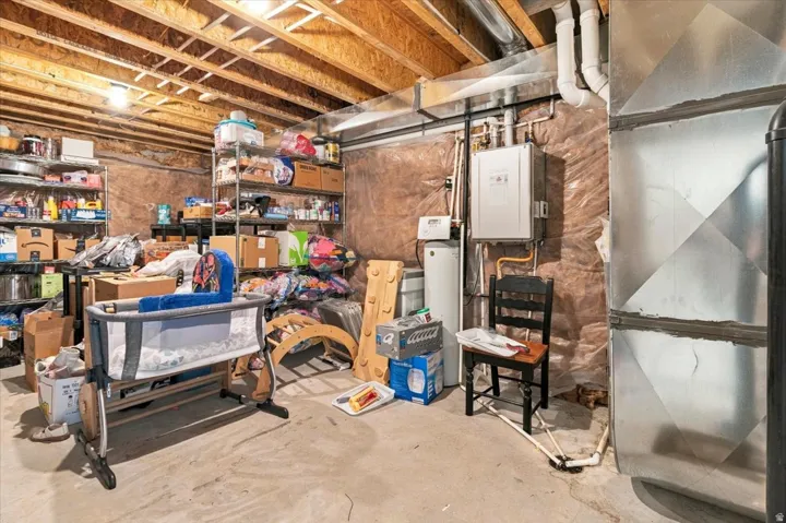 Unfinished basement with exposed ceiling joists, concrete flooring, and visible ductwork