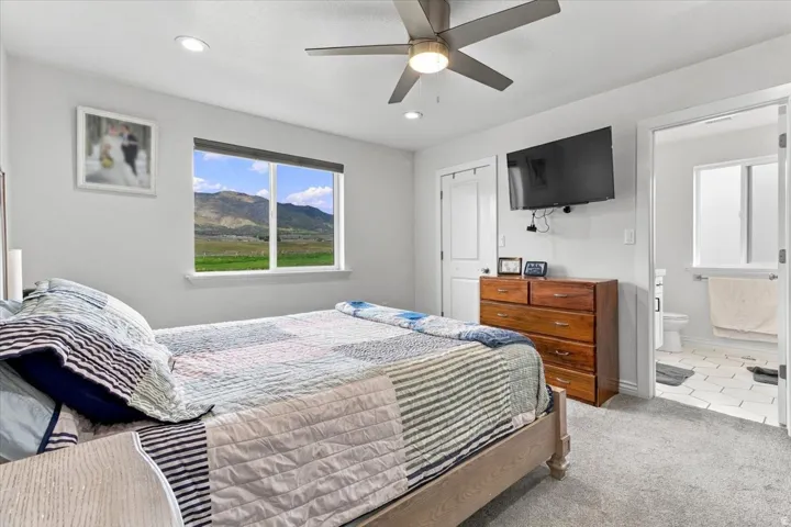 Carpeted room featuring a window with expansive outdoor scenery, a ceiling fan with integrated lighting, recessed ceiling lights, and a solid wood dresser
