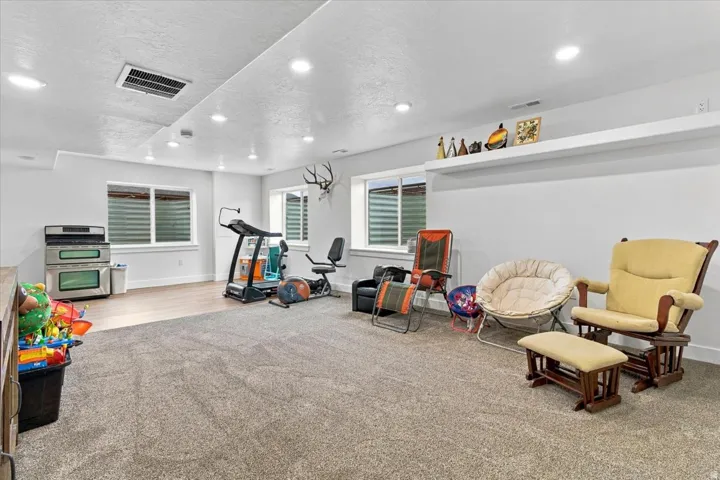 Recessed lighting, wood-finish flooring, two large windows, built-in shelving, and light-tone carpeting
