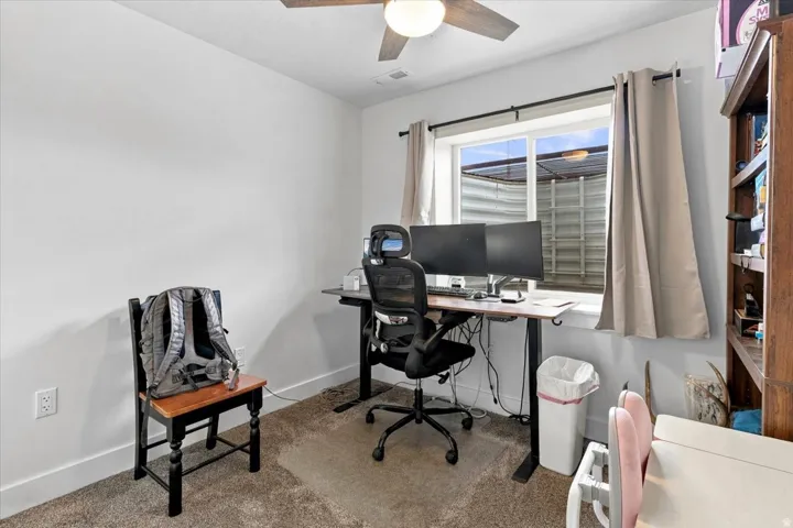 Carpeted flooring, a window with curtain rod and drapes, a ceiling fan with integrated lighting, and built-in shelving