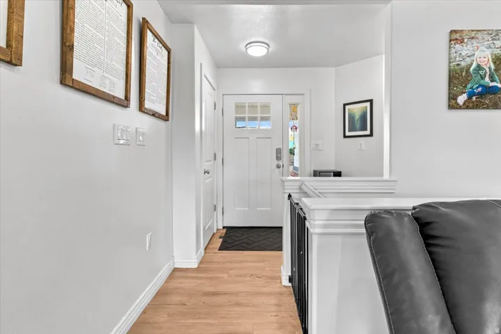 Entryway featuring a Craftsman-style door with glass panels, wood-finish flooring, a contemporary ceiling light fixture, and white painted balusters