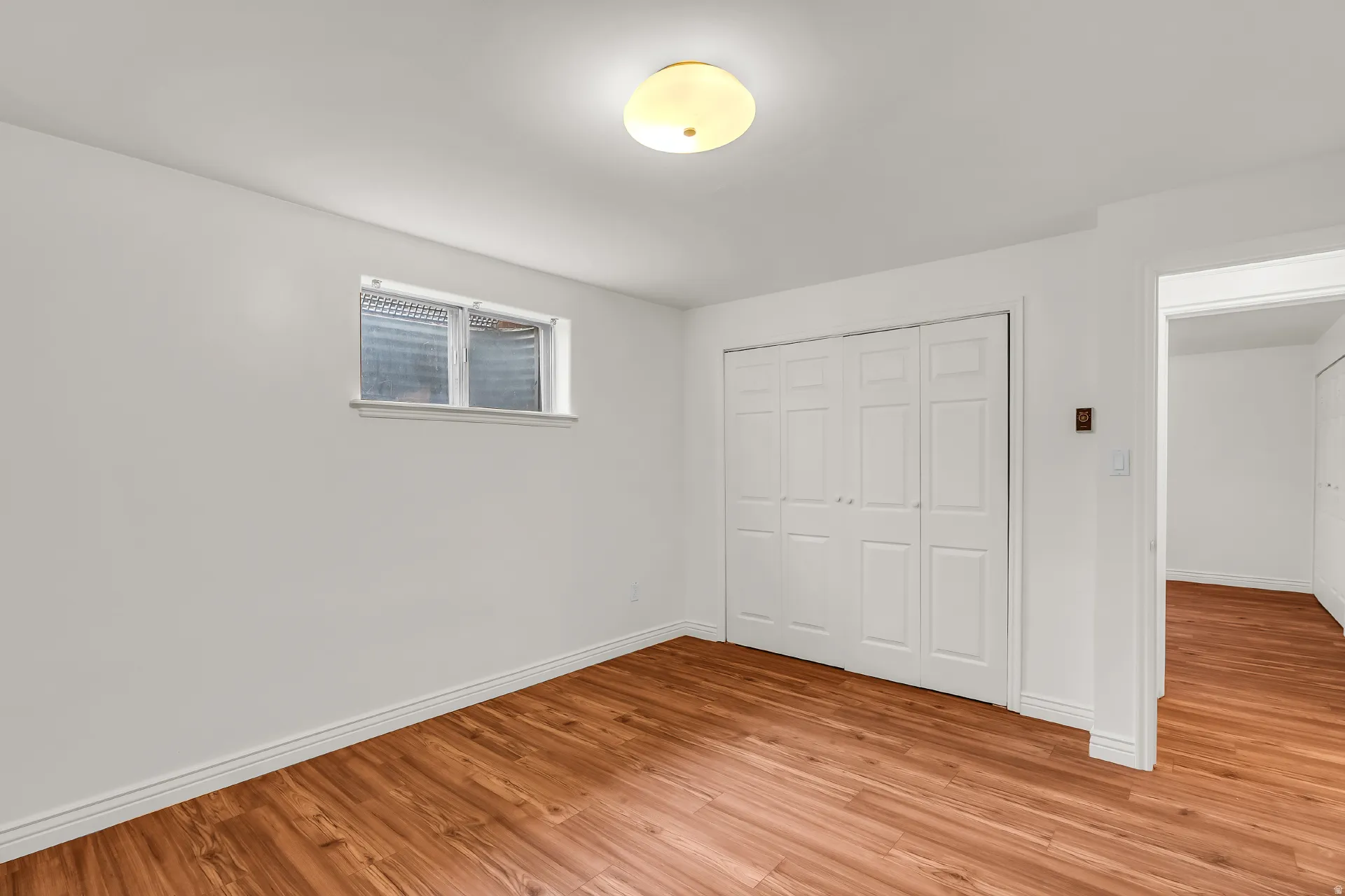 Recessed window, wood-finish flooring, bi-fold closet doors, and overhead lighting