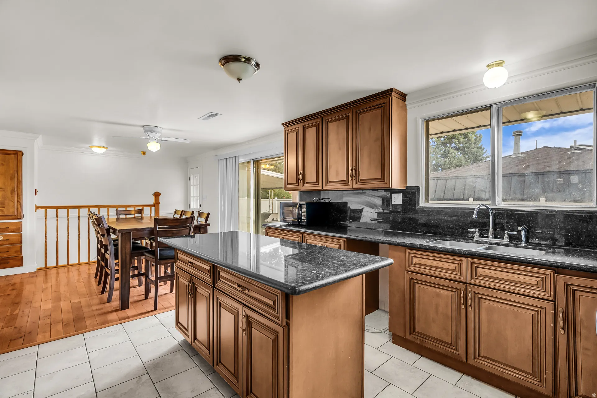 Kitchen featuring wood cabinetry, dark countertops, a central island, and a stainless steel sink