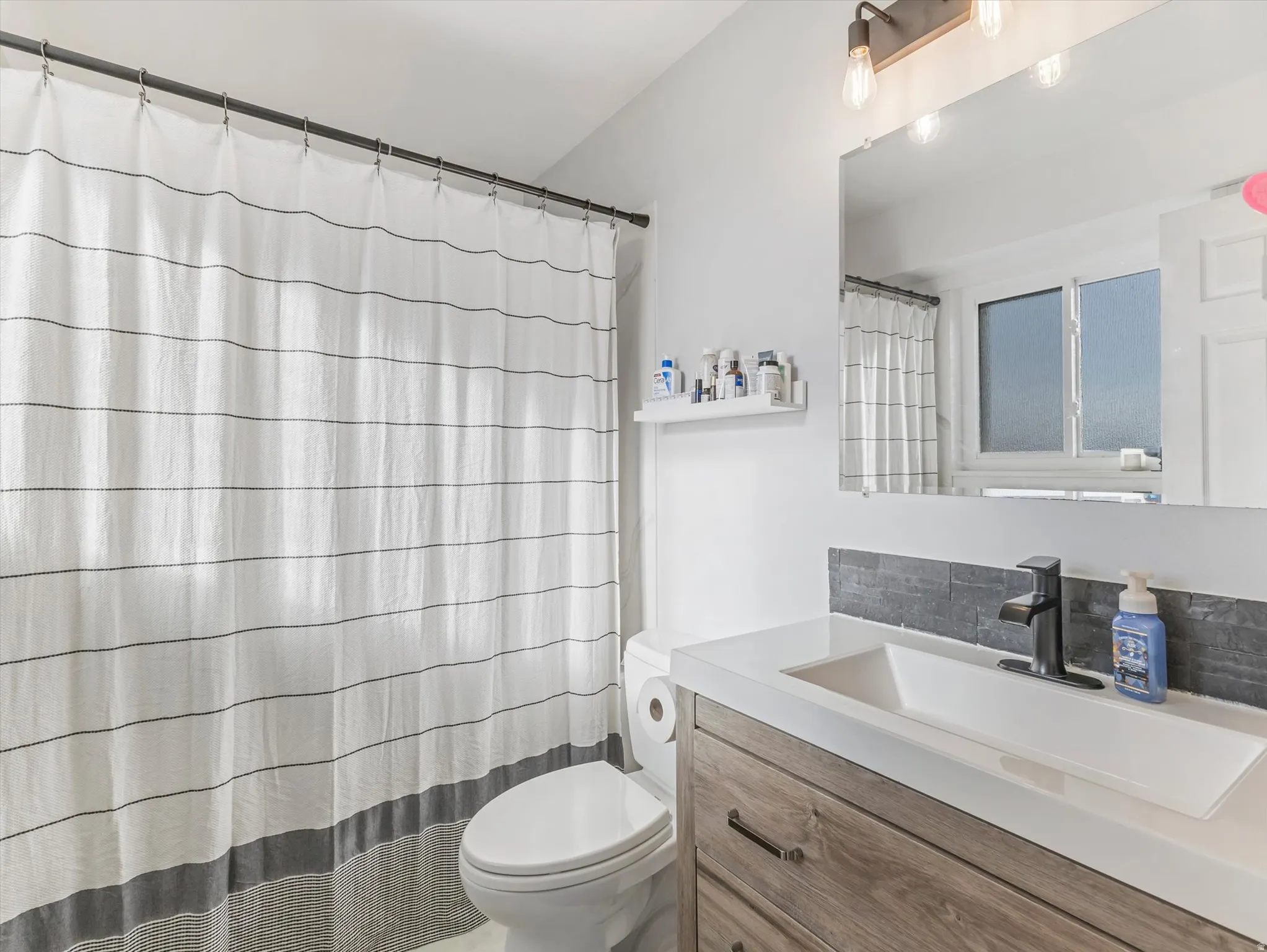 Vanity with wood-finish cabinetry, rectangular integrated sink, and matte black faucet