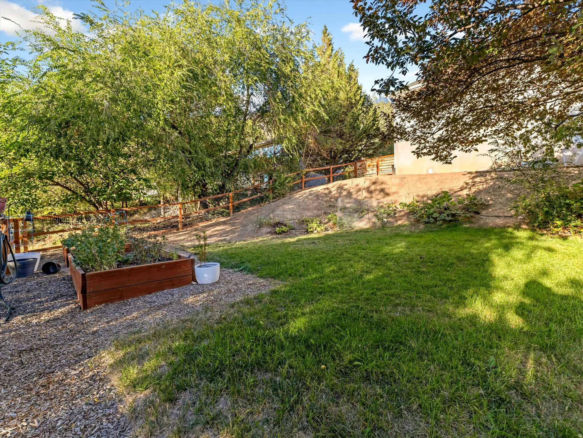 Expansive outdoor area featuring a manicured lawn, established landscaping, and a wood-finish raised garden bed