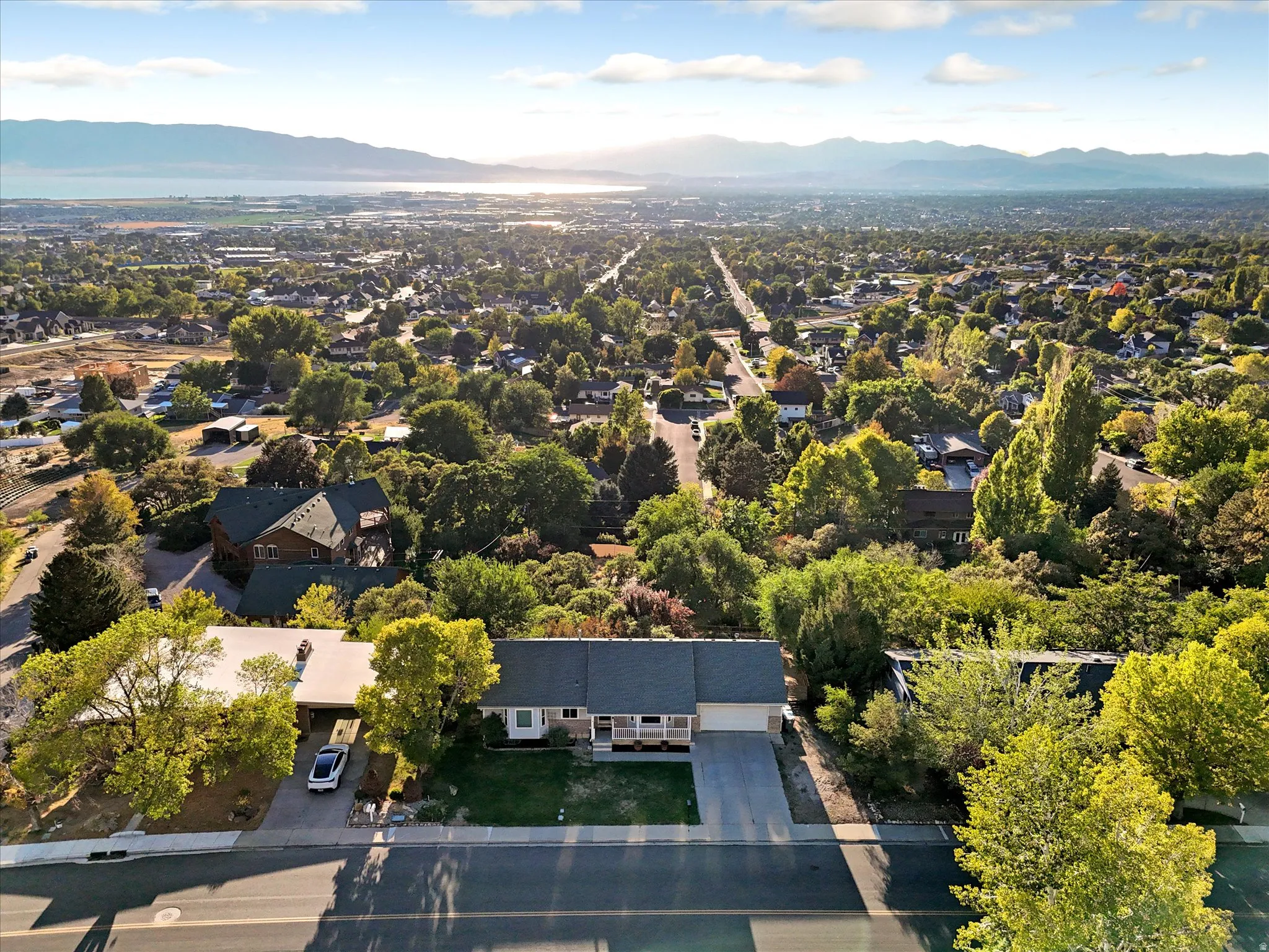 Expansive aerial capturing the residential area with a prominent mountain range and body of water in the background
