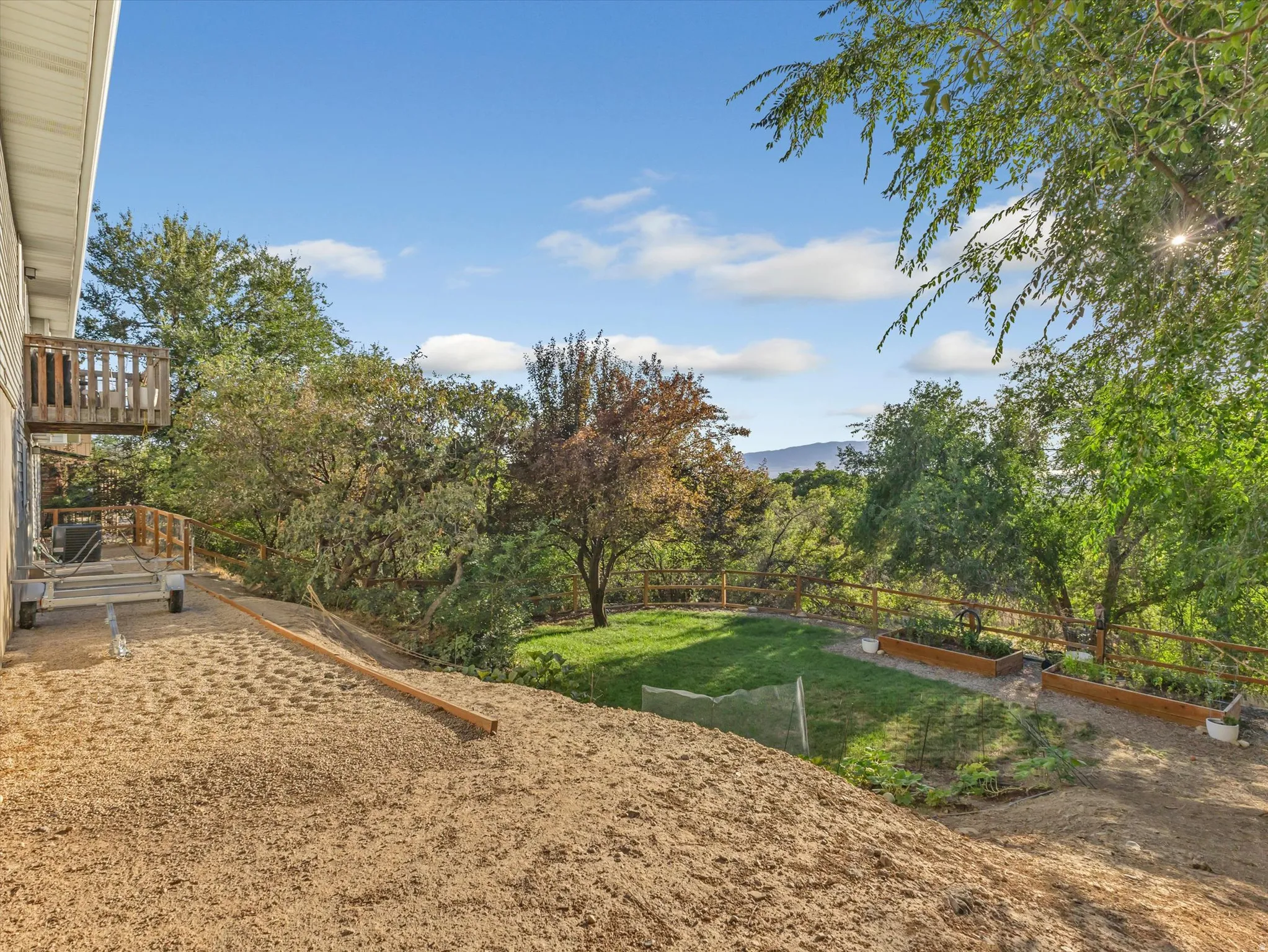 Multi-level outdoor space featuring a wood deck, sloped terrain, and a flat grassy area