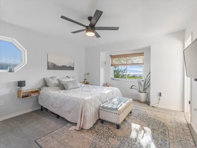 Vaulted ceiling with a contemporary ceiling fan, dual windows providing natural light, and light-toned wall finishes