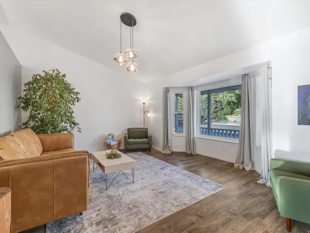 Vaulted ceiling, wood-finish flooring, bay window, and a contemporary three-light pendant fixture