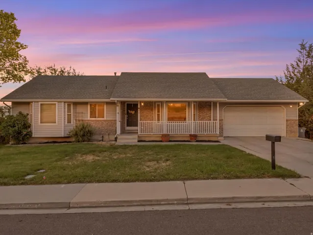 Ranch-style residence featuring a covered front porch with white railings, a two-car garage, and a concrete driveway