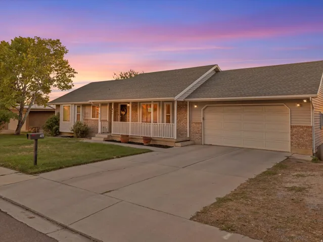 Exterior featuring siding and brick accents, an attached garage, a covered front porch with white railings, and a concrete driveway