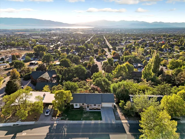 Expansive aerial capturing the residential area with a prominent mountain range and body of water in the background