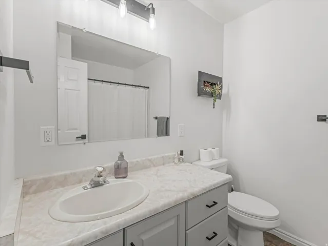 Bathroom vanity featuring a single basin sink, laminate countertop, and gray cabinetry with black hardware
