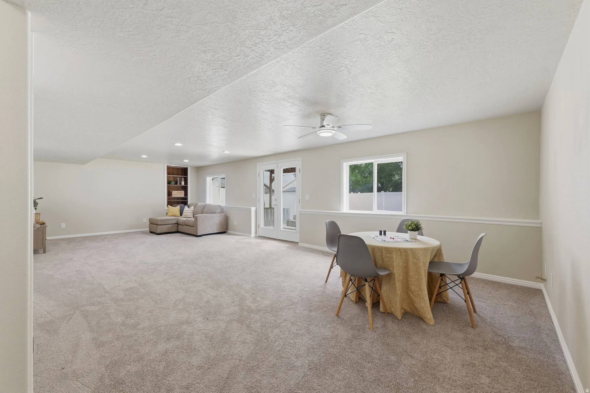 Expansive carpeted room featuring a ceiling fan, recessed lighting, and access to backyard