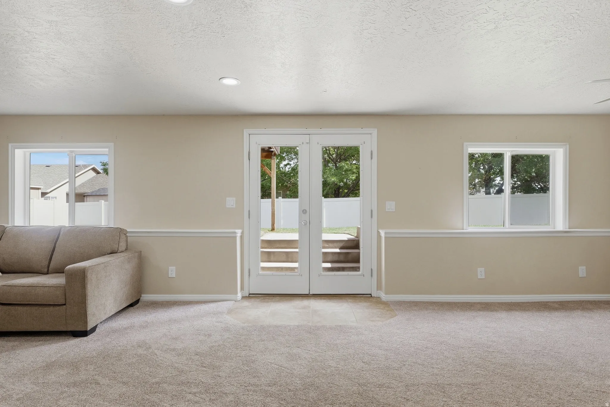 Carpeted room with recessed lighting, double-pane windows, and French doors leading to backyard