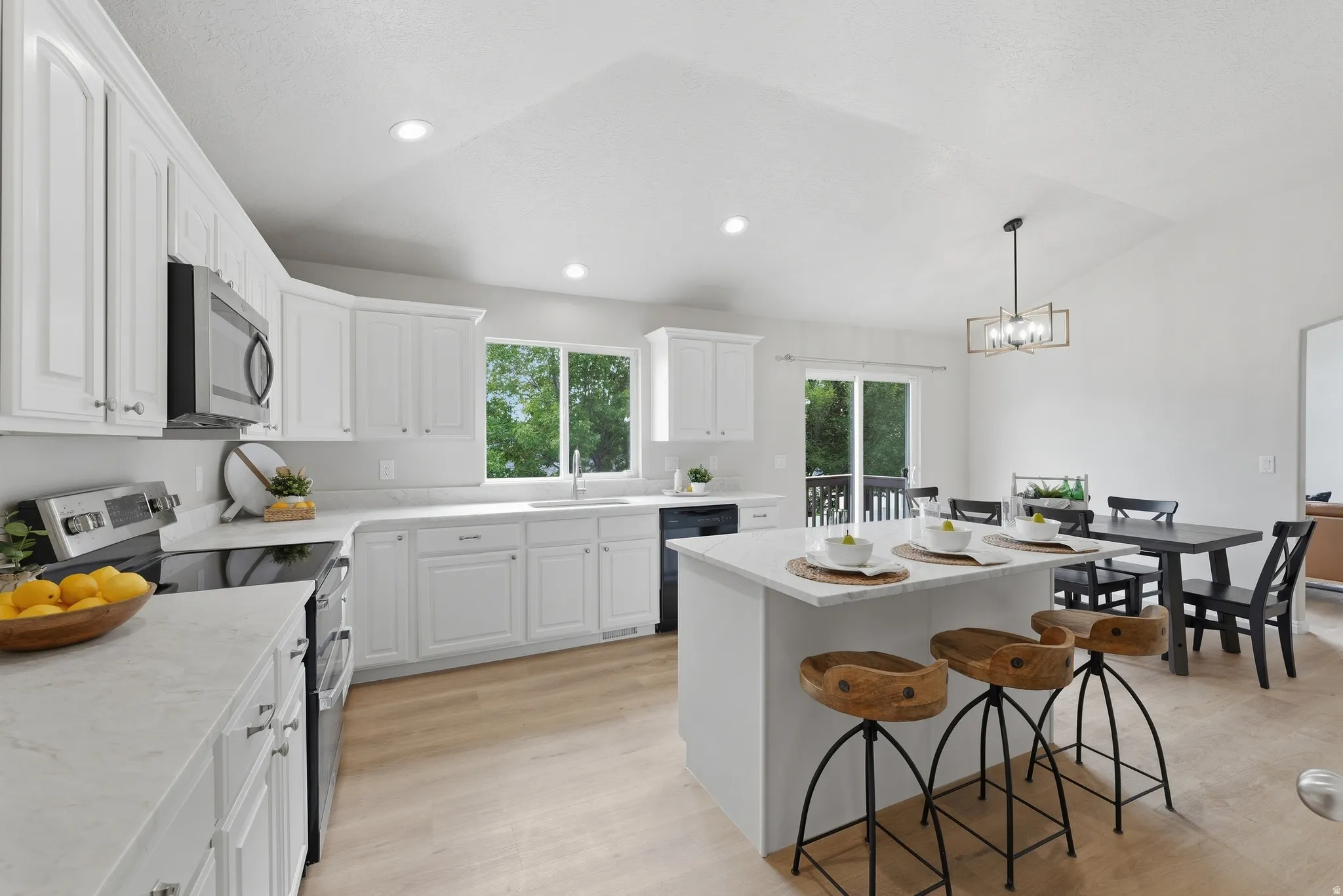 Kitchen featuring white cabinetry, light-toned quartz countertops, double oven, and wood-finish LVP flooring