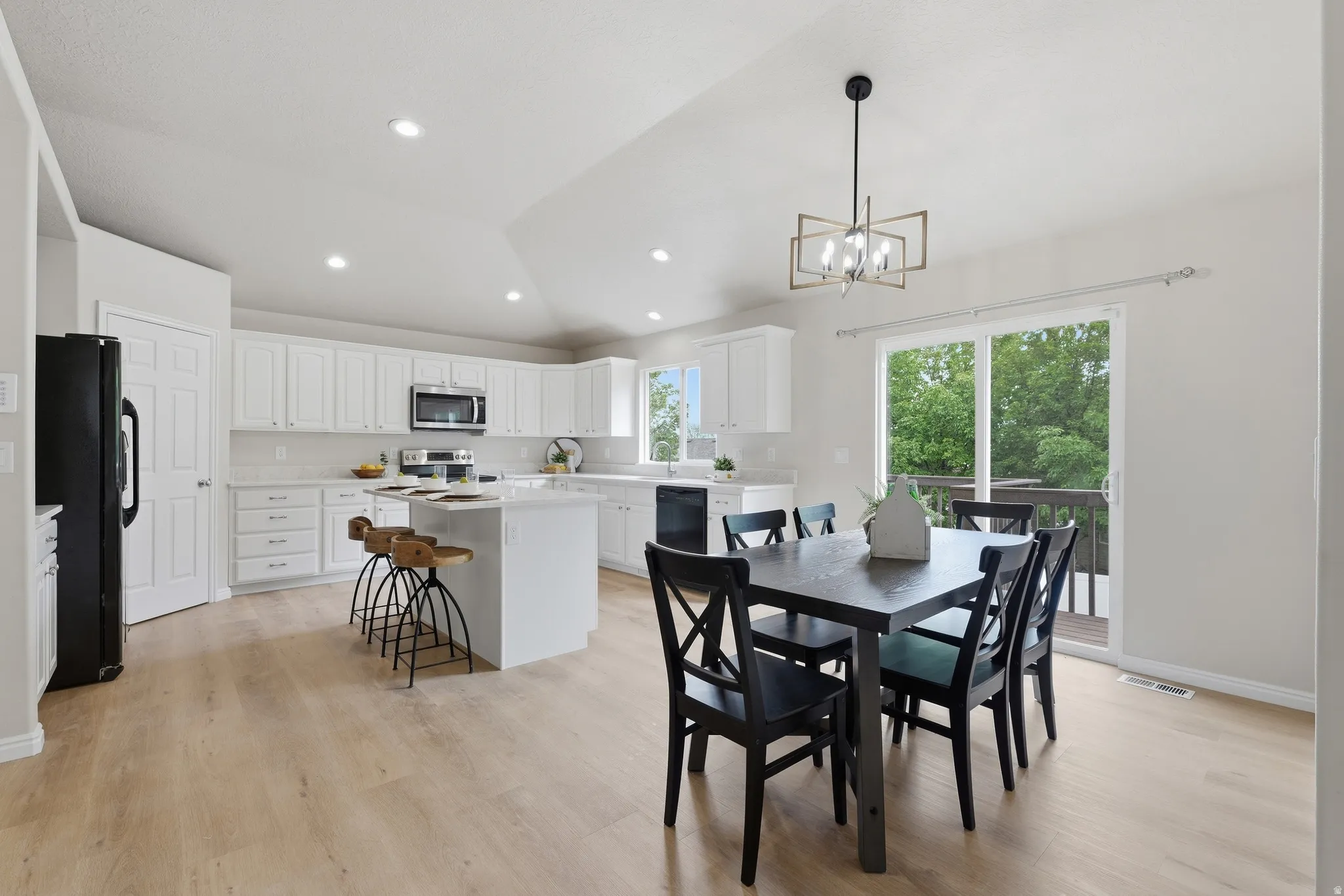 Open-concept kitchen with wood-finish LVP flooring, white cabinetry, a center island, quartz countertops and recessed lighting