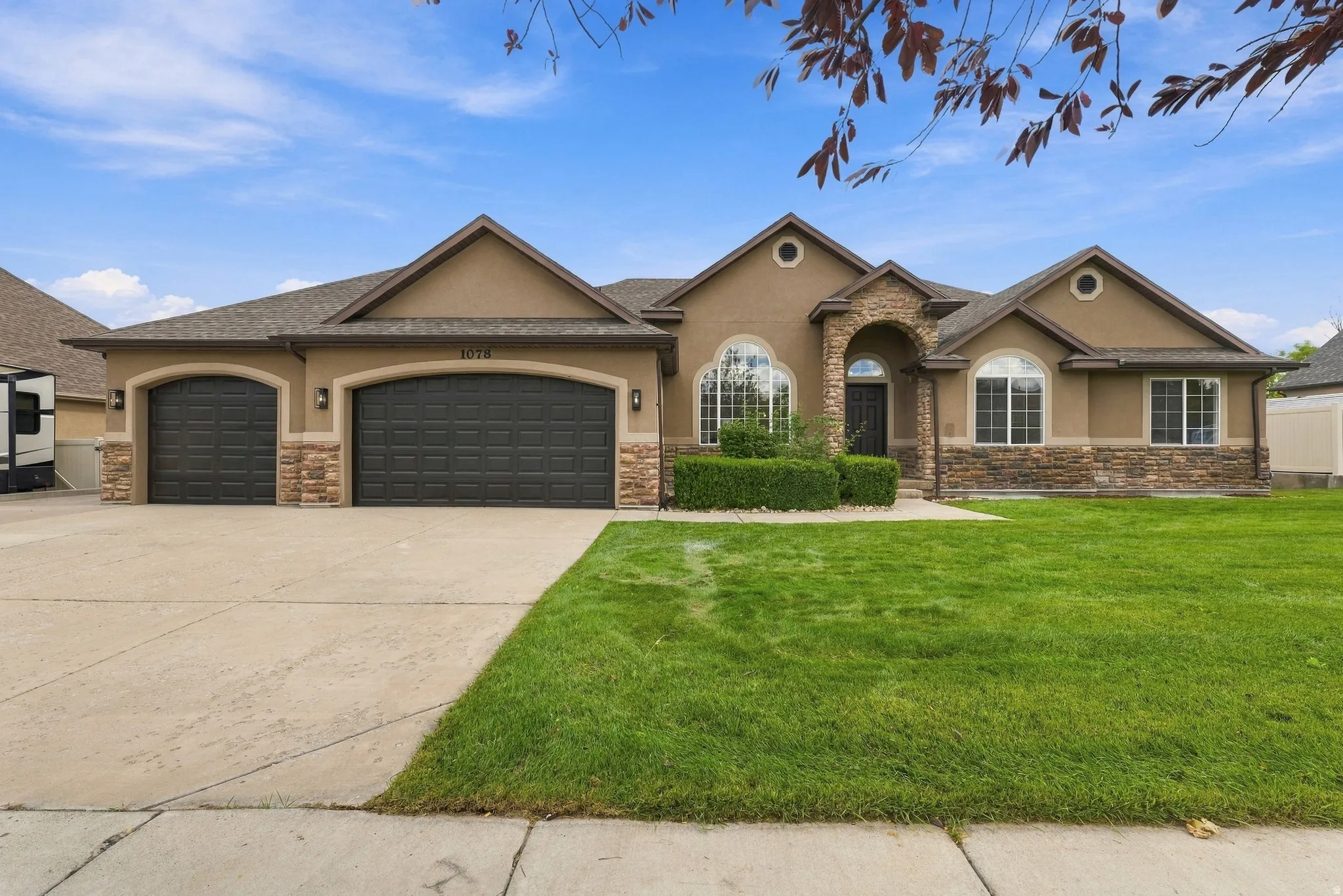 Stucco exterior with stone accents, arched entry, three-car garage, RV parking and manicured front lawn