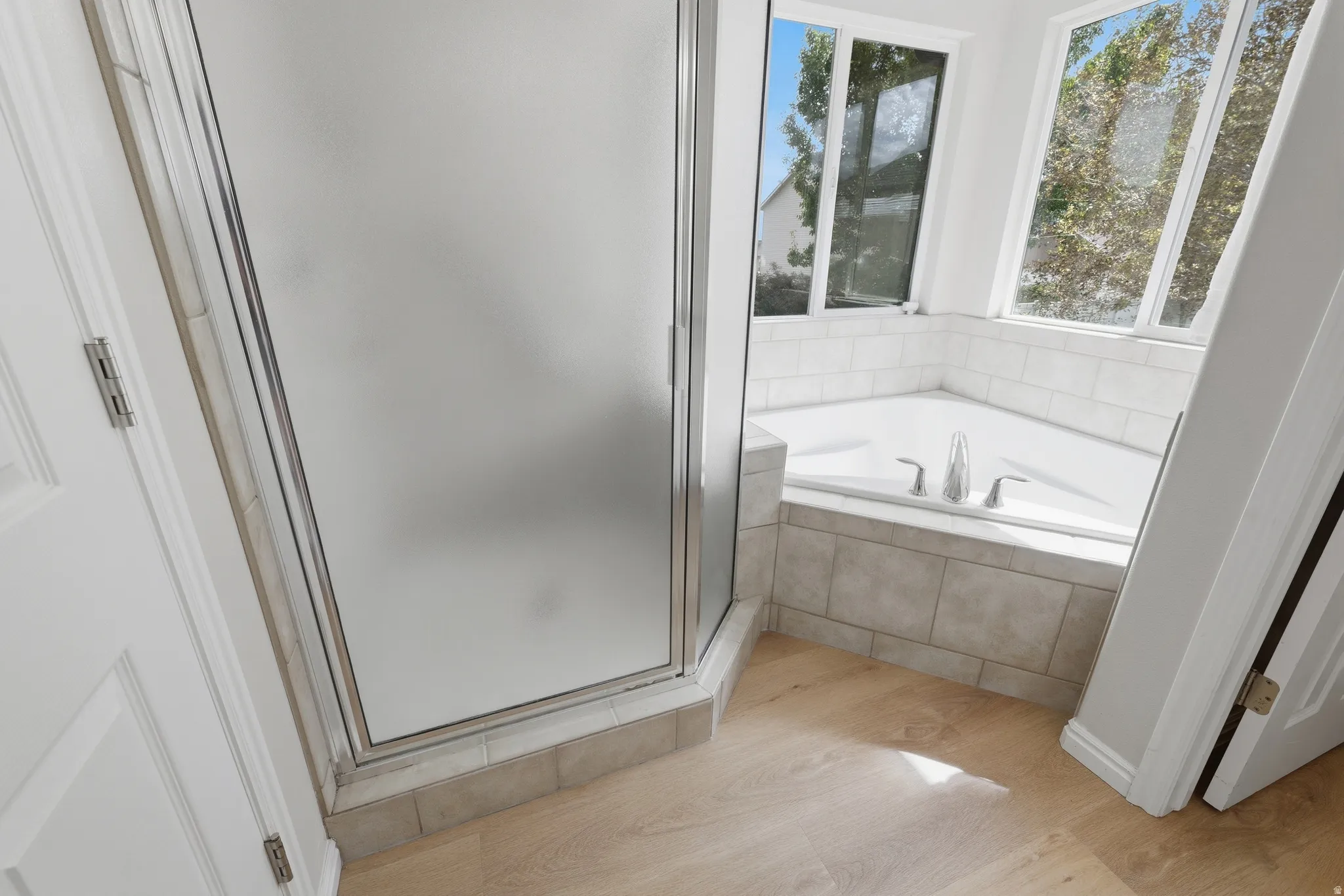 Frosted glass shower enclosure, built-in bathtub with tile surround, wood-finish LVP flooring