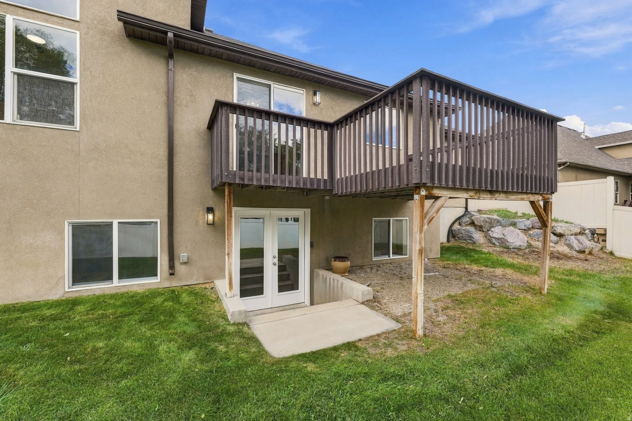 Raised wood-finish deck with dark railings, basement entrance
