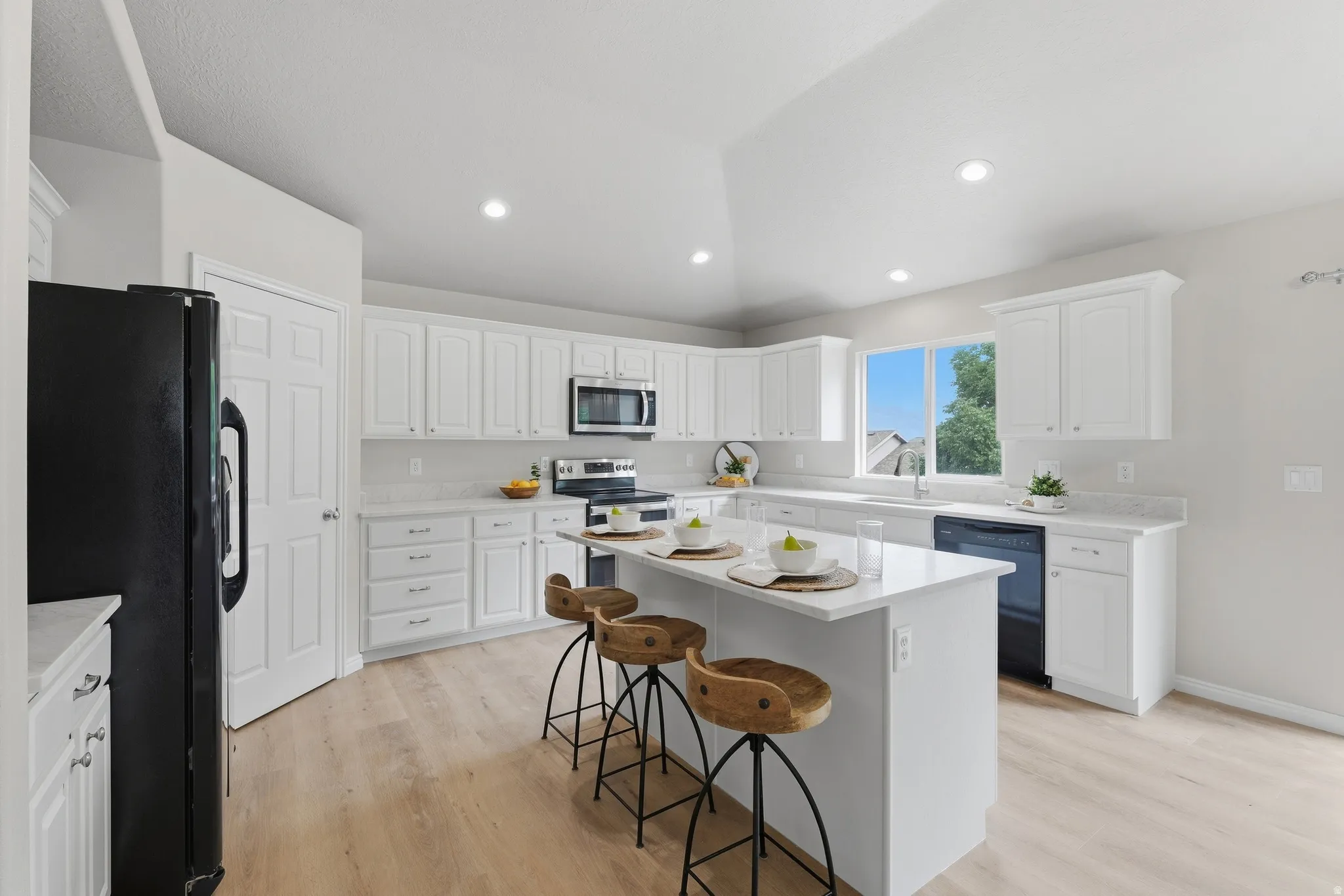 Kitchen featuring white cabinetry, quartz countertops, wood-finish LVP flooring, recessed lighting, and a large window