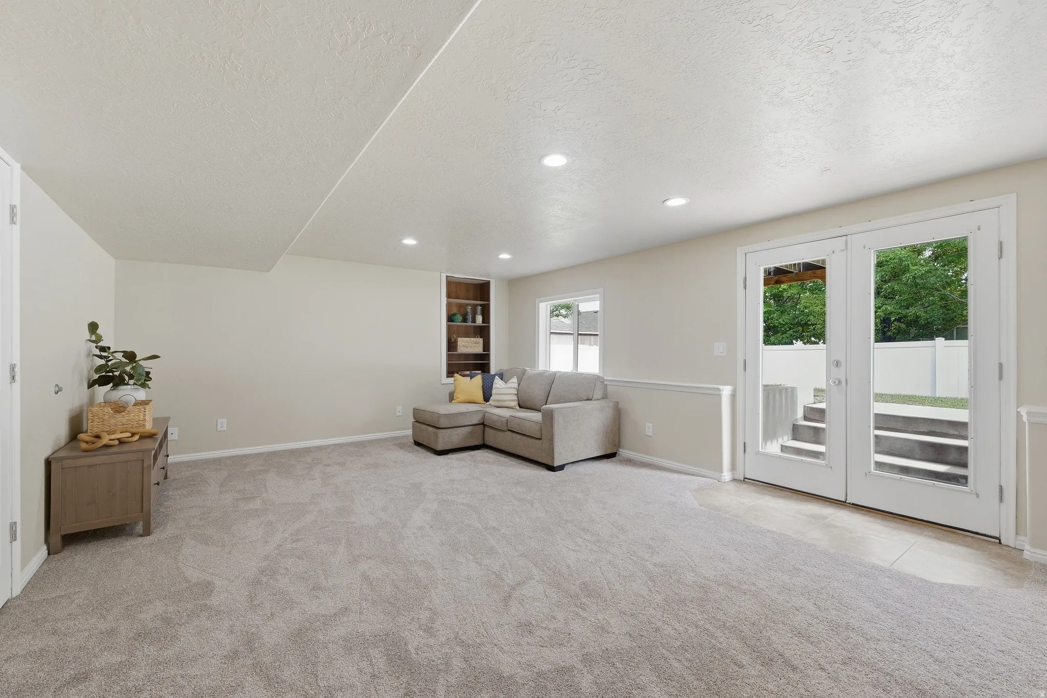 Recessed lighting, light-toned carpeting, glass-paned double doors with access to backyard